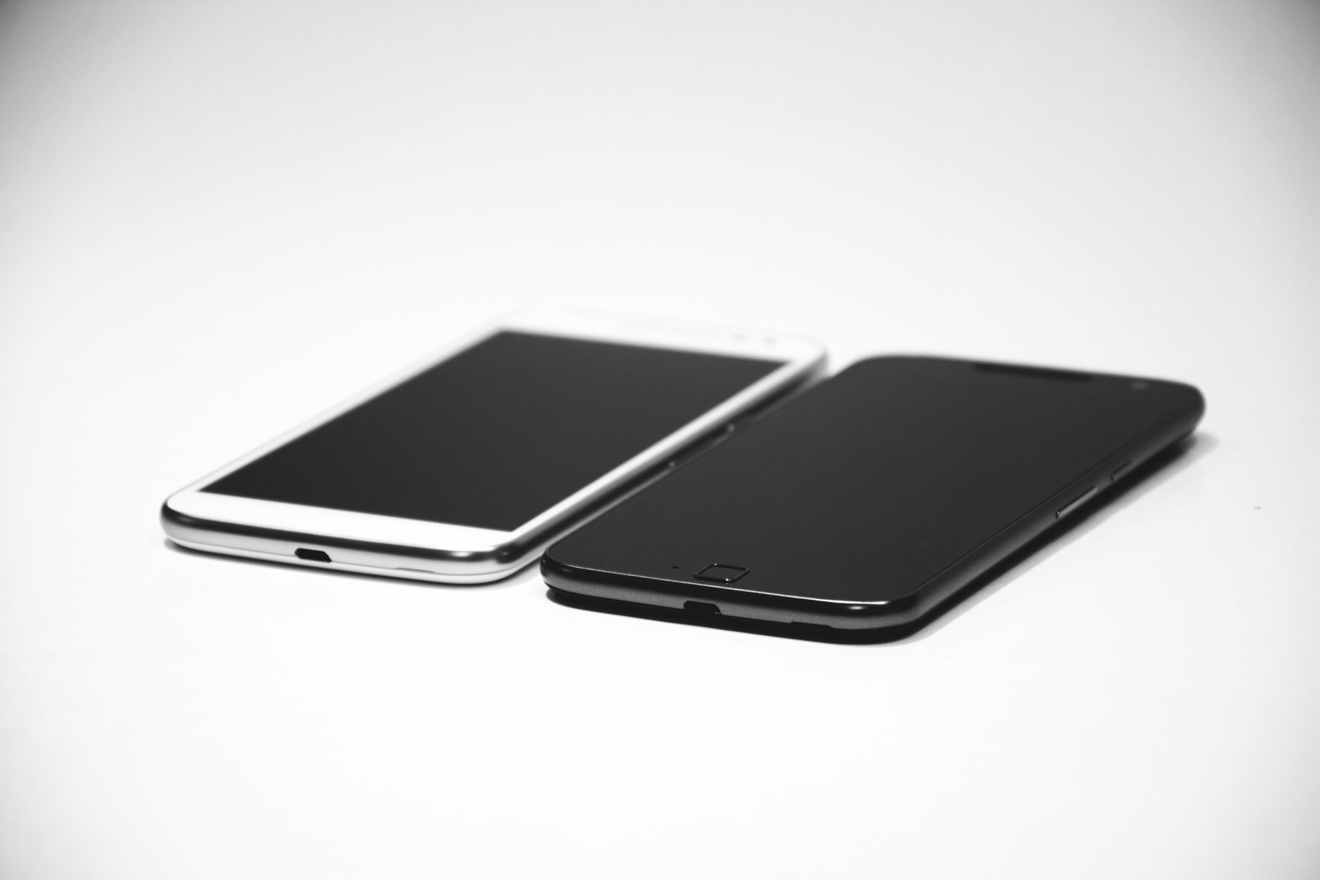 Deux smartphones, un noir et un blanc, placés sur une surface blanche, mettant en valeur un design moderne.