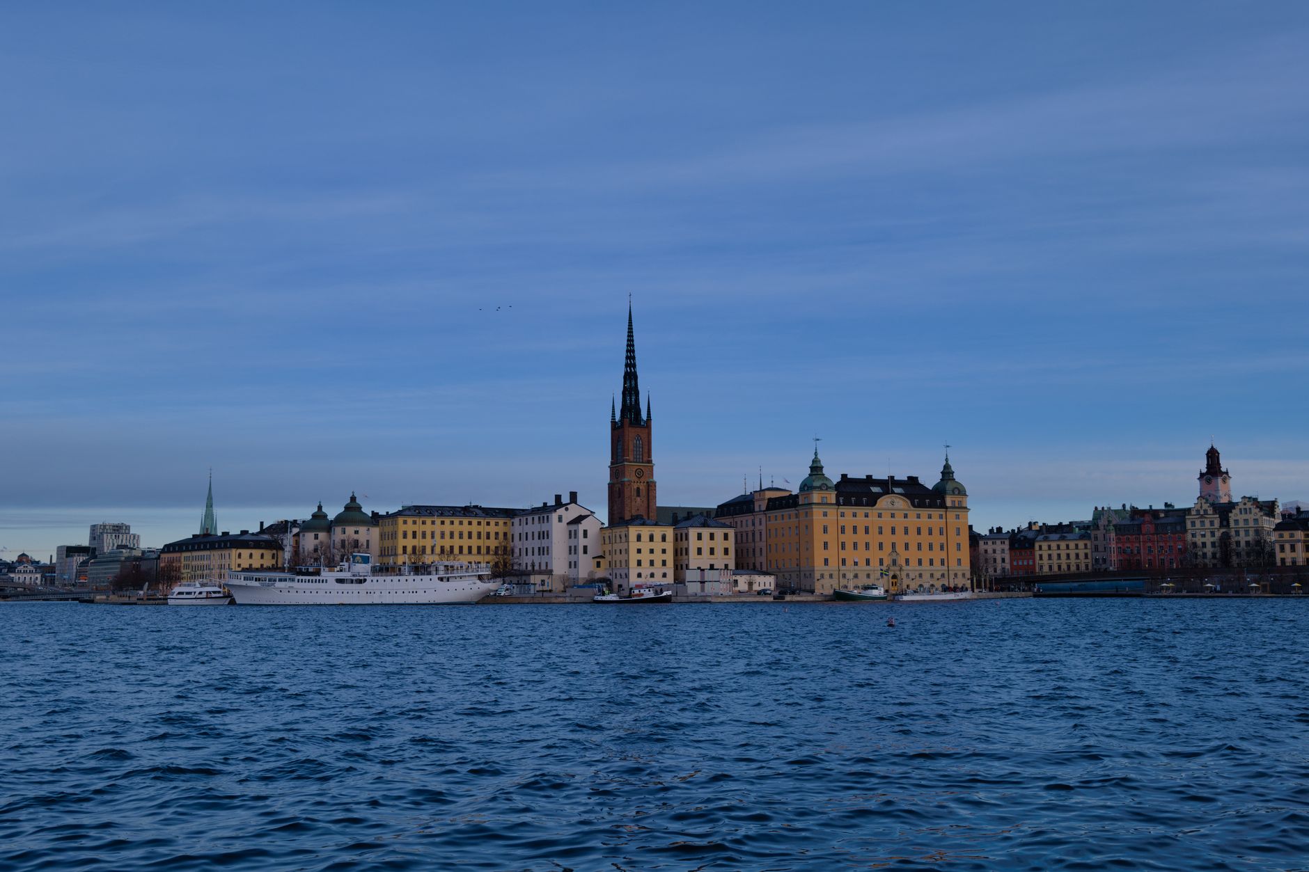 Skyline de Stockholm avec une architecture historique se reflétant sur l'eau sous un ciel clair.