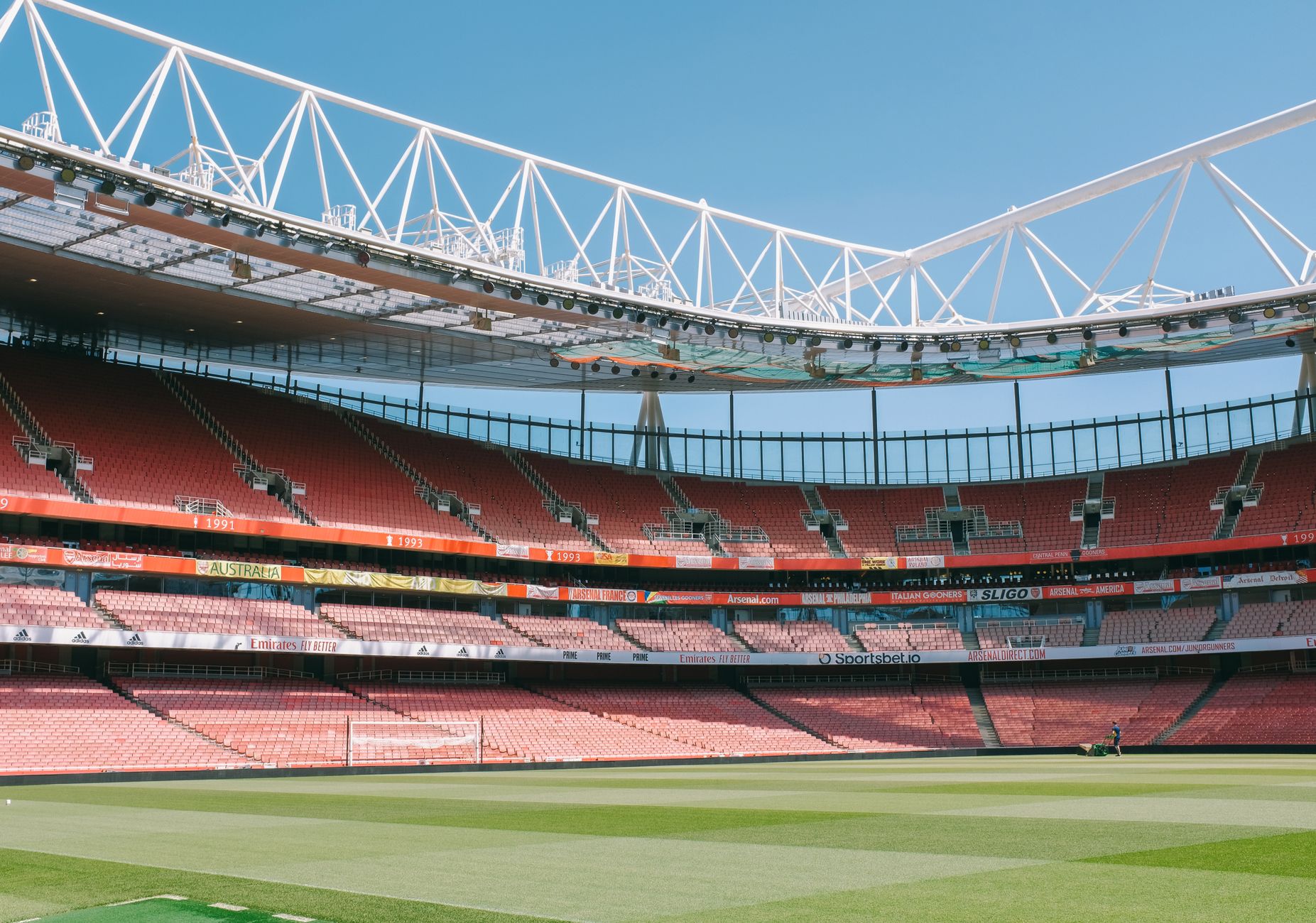 Vue large des tribunes vides du Stade Emirates sous un ciel bleu clair à Londres.