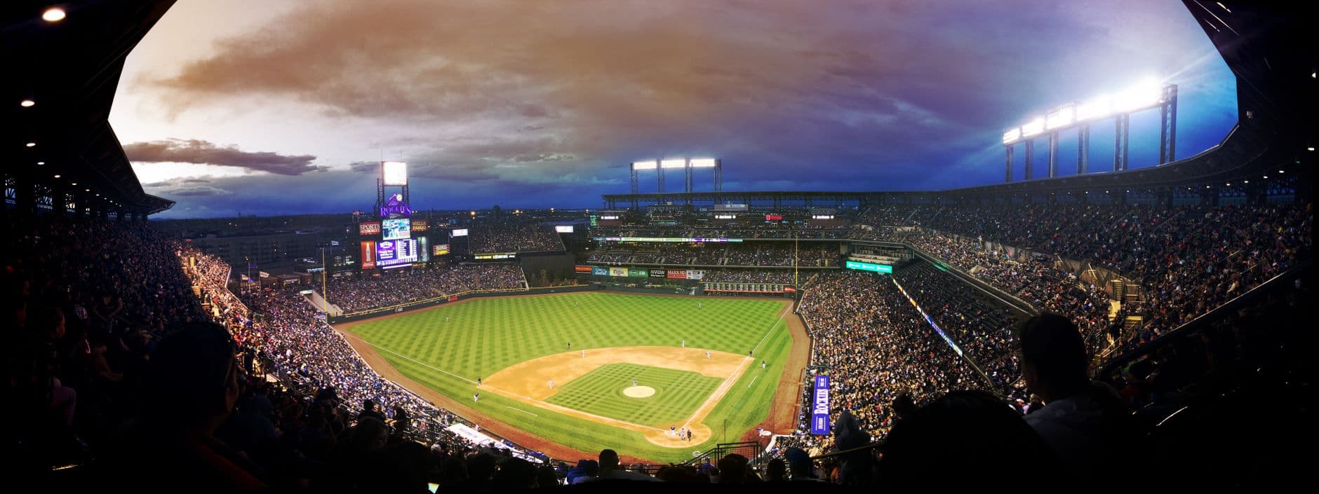 Vue grand angle d'un stade de baseball au crépuscule capturant le champ et la foule excitée.