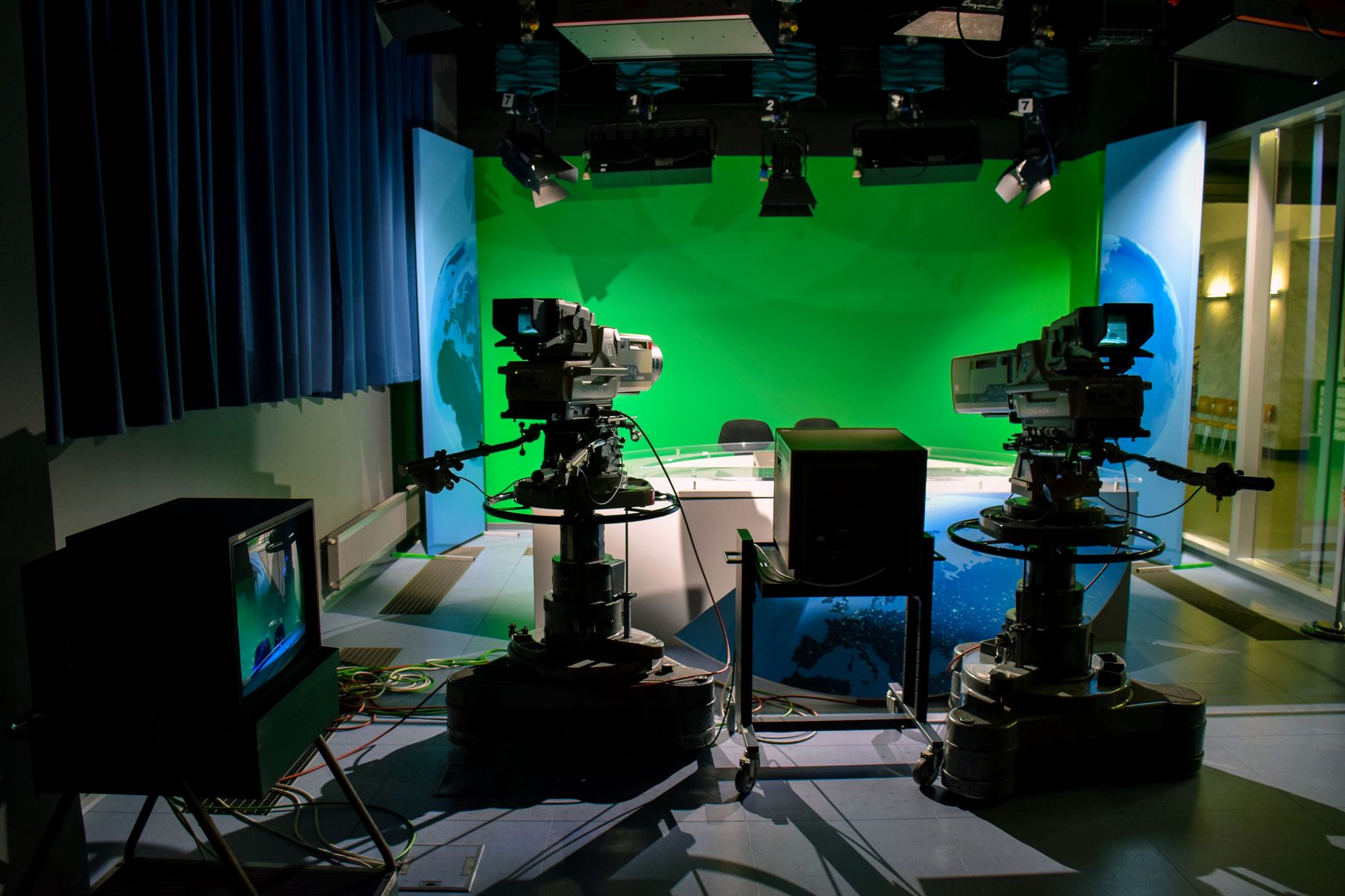 Un studio de télévision avec des caméras et un écran vert pour des besoins de production.